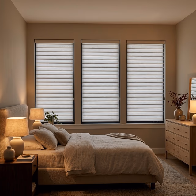 Hunter Douglas Aria fabric blinds with soft textile horizontal vanes tilted for room darkening in a modern-transitional bedroom with warm neutral tones and ambient bedside lighting, installed by Bay Blinds Novato CA 94945